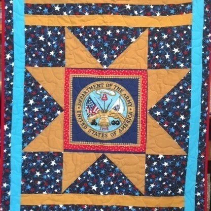 A veterans' quilt with a gold eight-pointed star around a Department of the Army seal, set against navy fabric printed with small stars